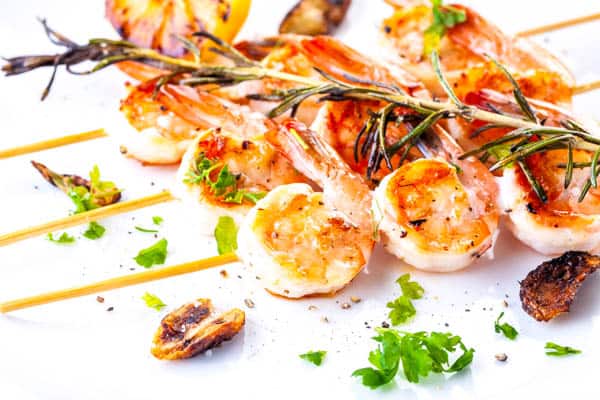 Grilled shrimp on skewers with grilled garlic and fresh herbs.
