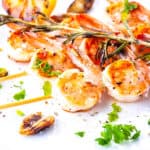 a plate of grilled shrimp and garlic with rosemary.
