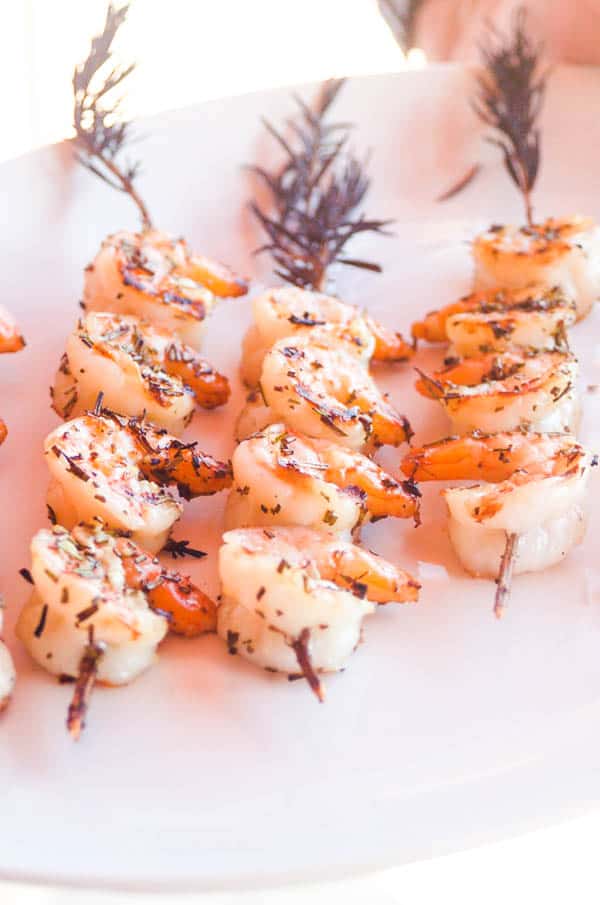 Rosemary skewered grilled shrimp on a plate. 