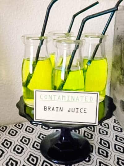 Glass jars with bright green juice that say zombie juice on it with straws.