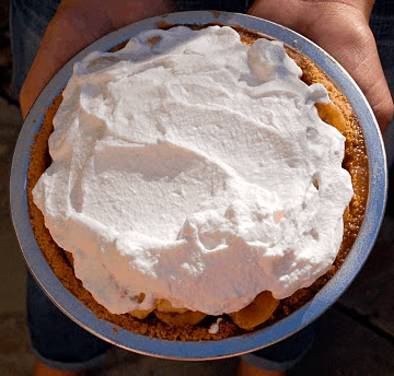 Overhead of a woman holding a pie topped with whipped cream.