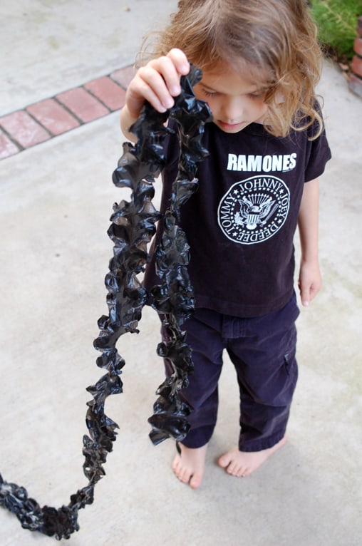 Boy holding ruffled streamers made out of plastic tablecloths or trash bags. 