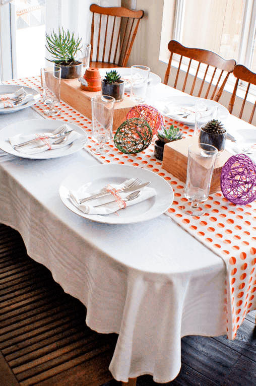 A dining table decorated for Easter with plates and yarn eggs.