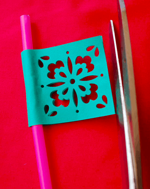 Close up of a straw with a paper flag punched out to look like a Papel Picado.