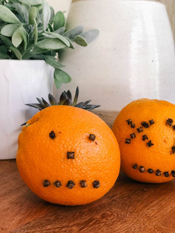 Orange studded with cloves to make pumpkin faces