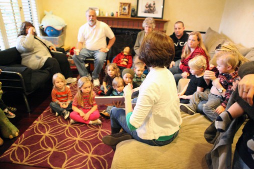 A women reading a book to a group of kids.