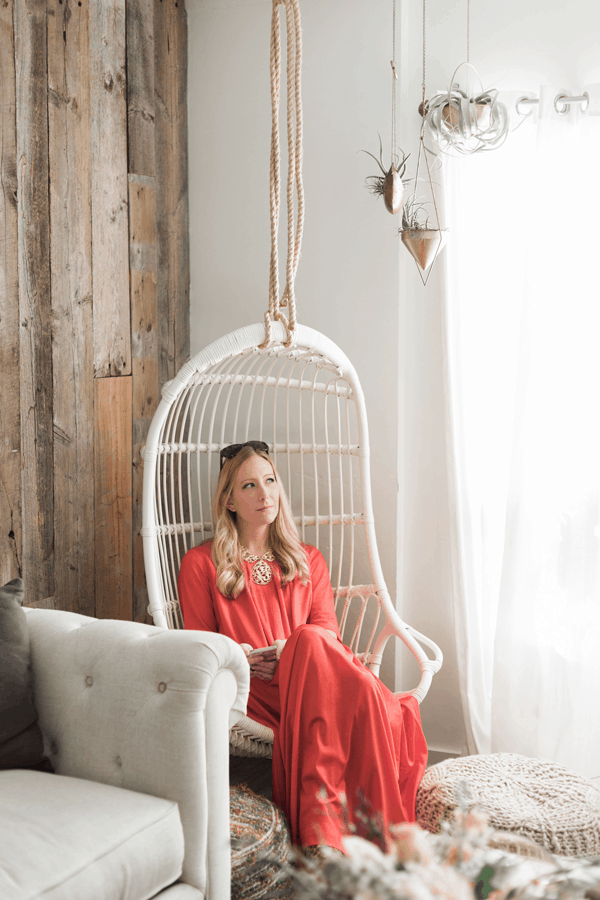 Sharon Garofalow sitting in a hanging chair in a living room.