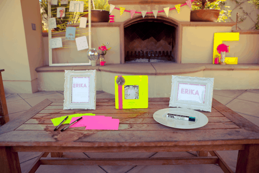 Picture frames on an outdoor table in front of a fireplace. 
