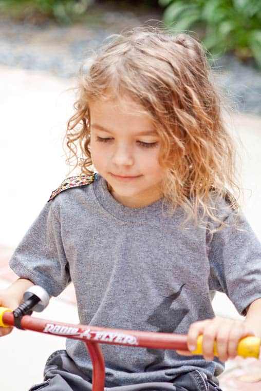 Close up of a kid on a tricycle.