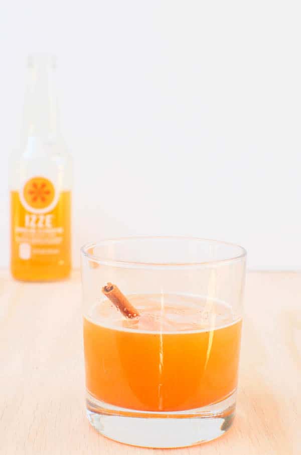 Cocktail in a glass on a wooden board with and Izze Soda in the background.