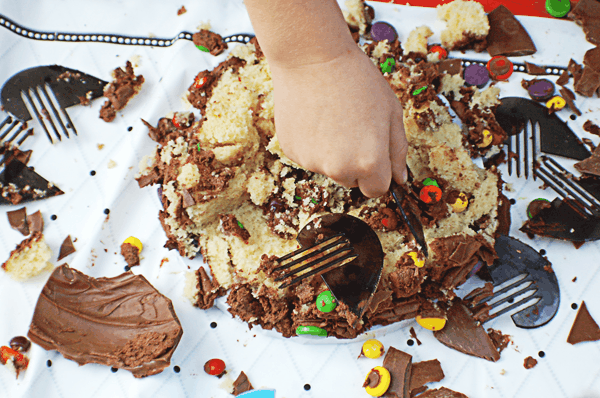 A smashed cake with kids using heart-shaped utensils to dig in.