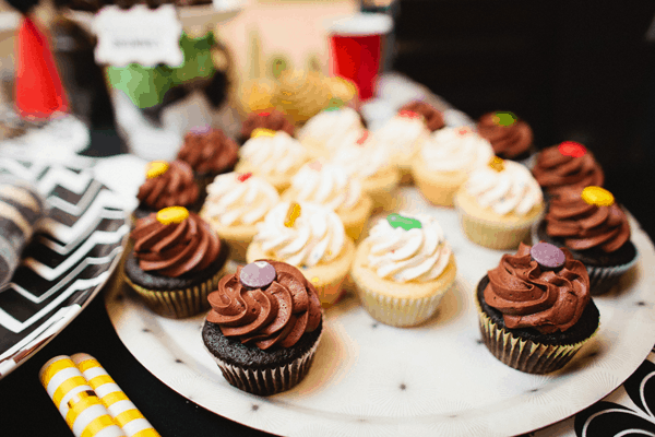 A tray of frosted cupcakes on a table for a kid's party.