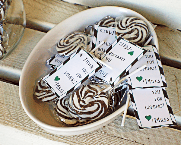 A bowl holding black and white swirled suckers as a party favor. 