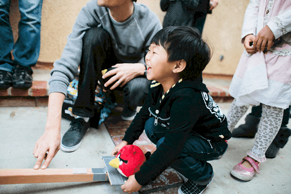 A boy using a catapult to make a stuffed Angry Bird toy fly.