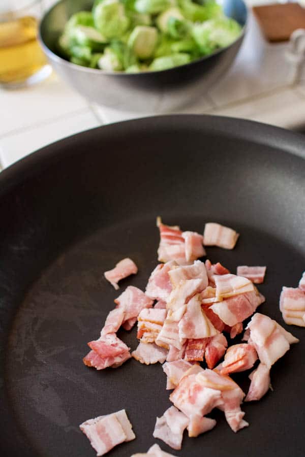 Chopped bacon cooking in a pan for braised brussels sprouts.