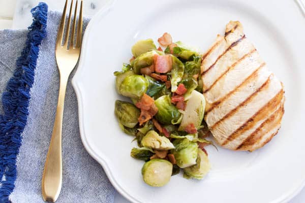 sauteed brussels sprouts with bacon on a plate with chicken