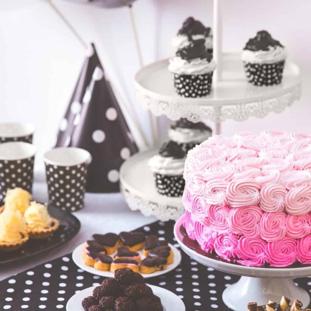 A pink ombre cake on a party table with black and white party decor.