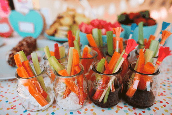 Glass jars with dip and vegetables sticking out. 