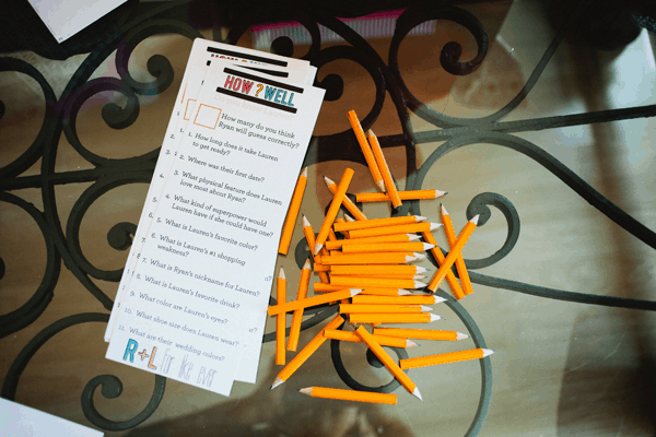 A stack of bridal party game cards on a table next to pencils. 