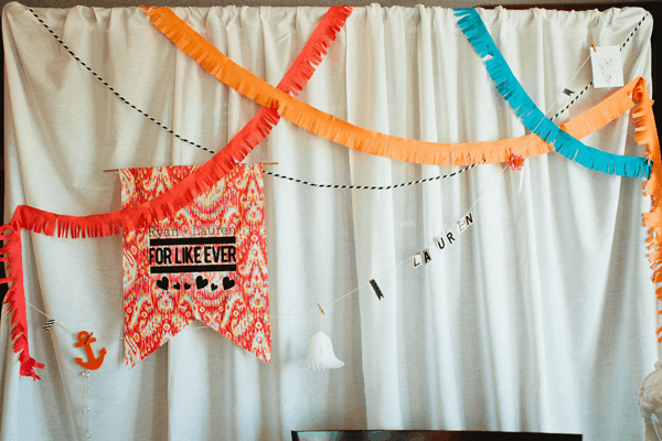 Close up of a backdrop for a party with garlands and a sign.