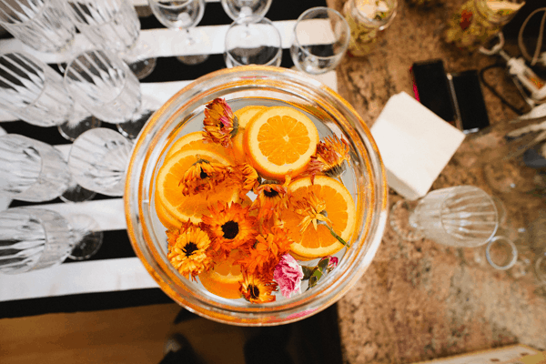 Overhead shot of water topped with orange slices and edible flowers for a party.