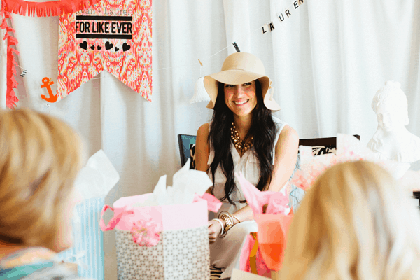 A woman sitting in front of gifts at a bridal shower. 