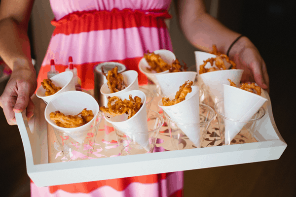 Woman holding a tray of paper cones holding funnel cakes. 