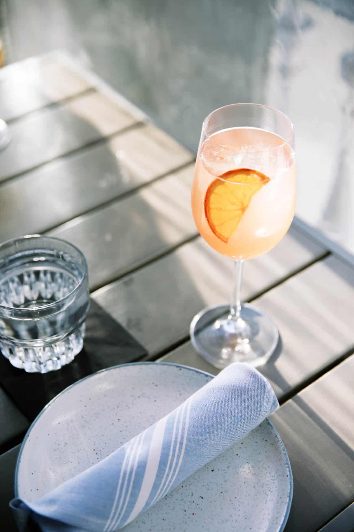 A spritz in a wine glass on an outdoor table.