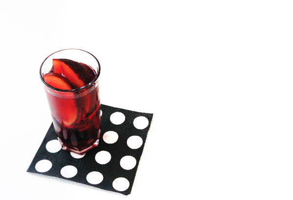 Warm plum sangria in a glass with plums on a table. 