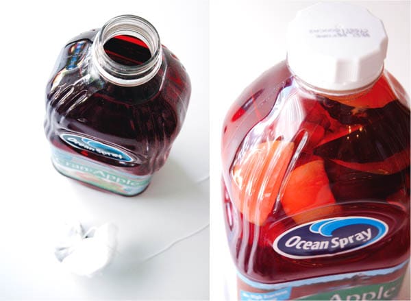 A bottle of Ocean Spray apple cranberry juice on a table with a spice bundle next to it.