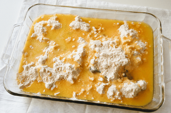 A glass baking dish with dry cake mix topped with melted butter.