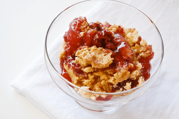 A serving of our favorite Pineapple Cherry Dump Cake in a footed glass dessert bowl.