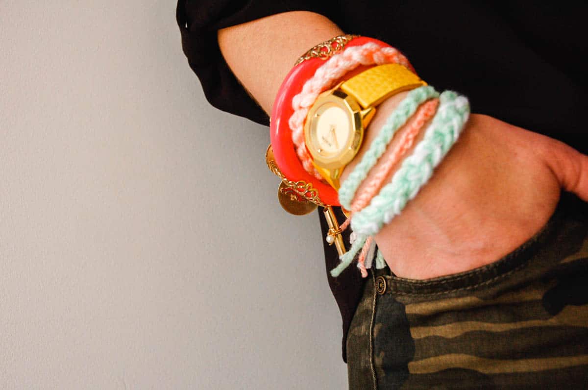 A woman's hand in her pants pocket with a bunch of knotted yarn bracelets on.
