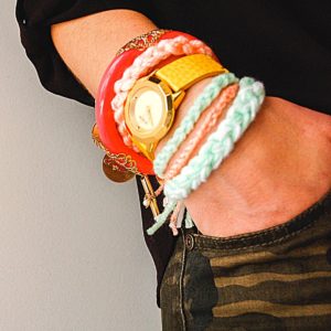 Close up of a woman wearing knotted yarn bracelets.