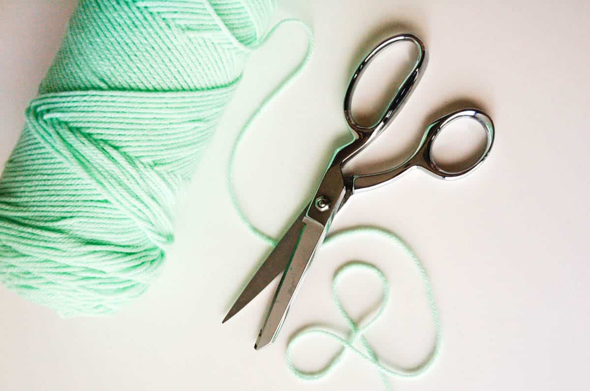 A spool of yarn next to a pair of scissors.
