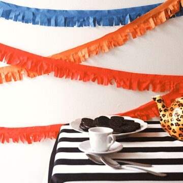 Fringed party garland on a wall behind a small table.