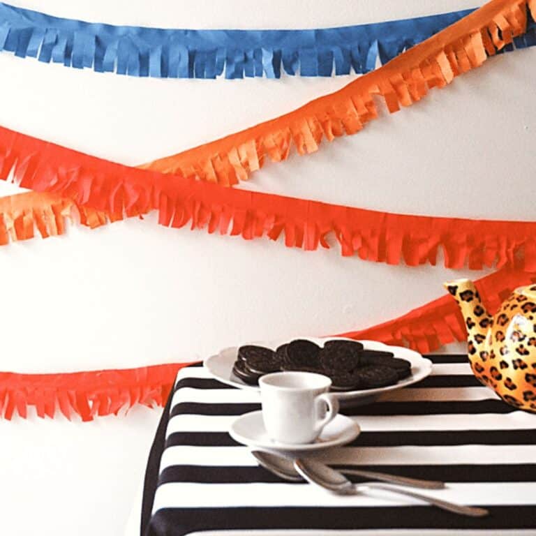Fringed party garland on a wall behind a small table.