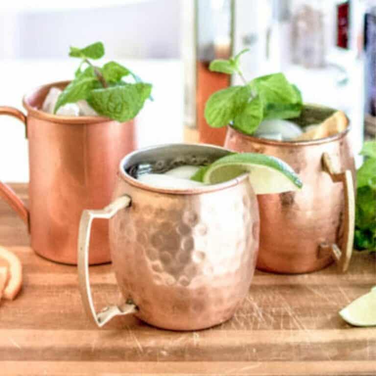 Moscow Mules in a variety of copper mugs on a counter.