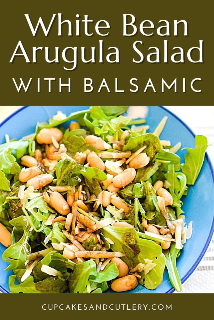 A bowl of salad with arugula, white beans and parmesan with text that says "White Bean Arugula Salad with Balsamic".