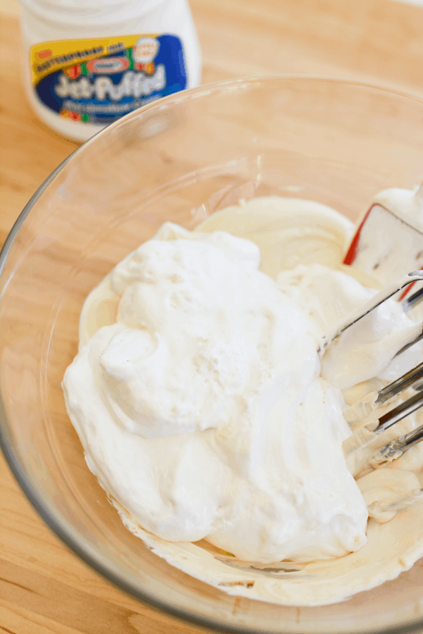 A bowl with whipped cream cheese and marshmallow cream about to mixed in. 