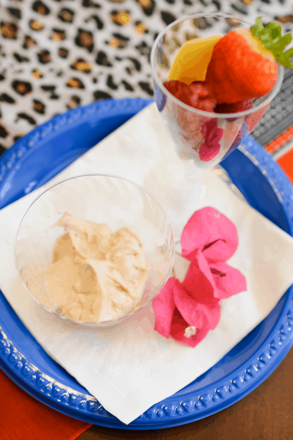 Overhead view of a cup holding fruit dip next to a cup holding fruit. 