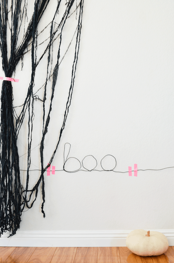 Boo sign made of wire for Halloween and stuck to the wall with pink tape.