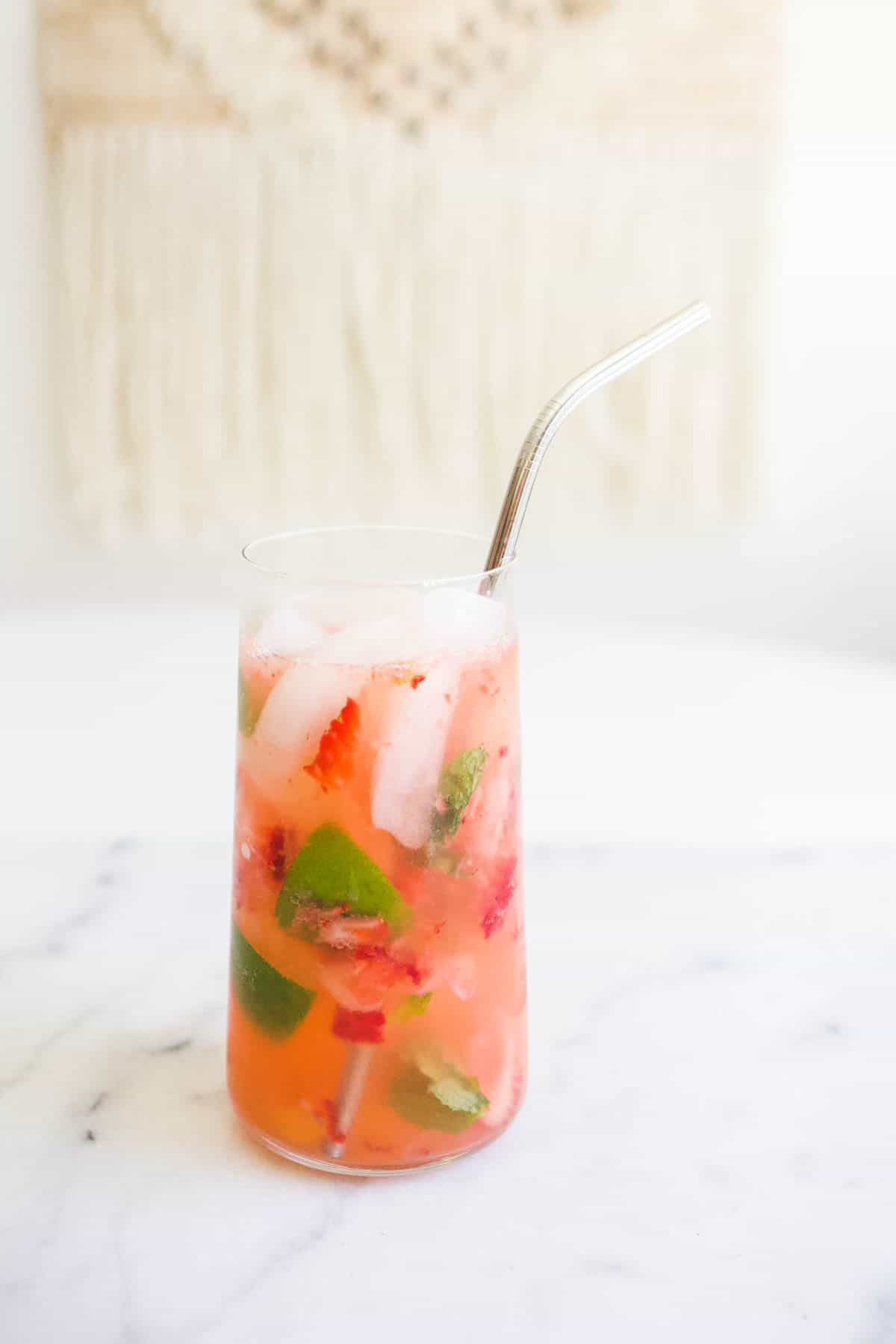 A flavored sparkling water with muddled pieces of strawberry, mint and ginger floating in it. 