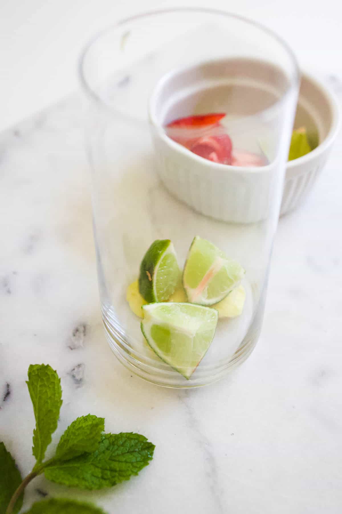 Sliced ginger and lime chunks in the bottom of a glass.