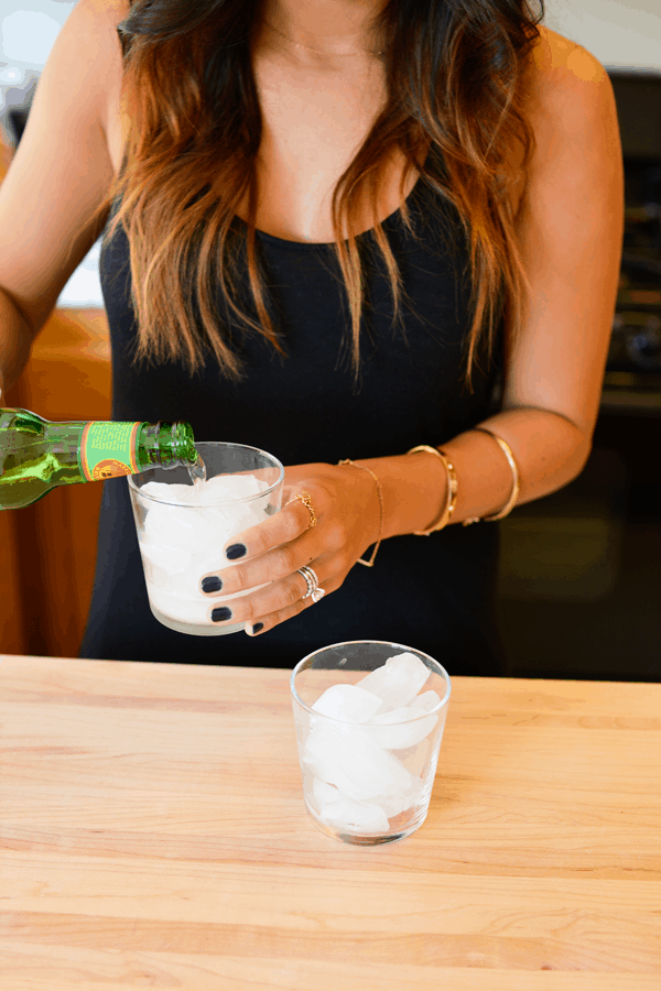 Girl pouring ginger beer in a glass for a girl's night in dinner party.