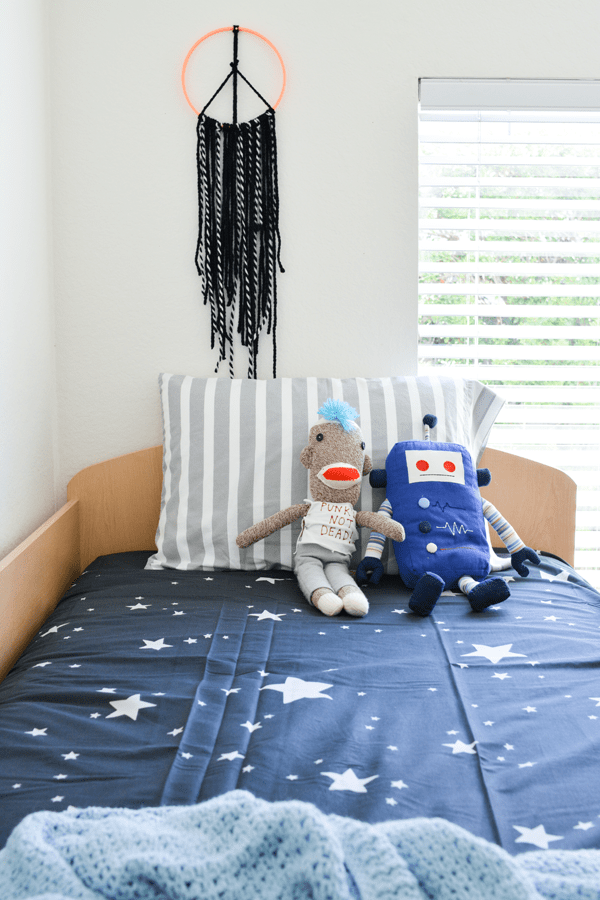 Kids room with a peace sign wall hanging above the bed.