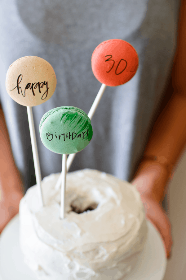 Macarons written on with edible ink and placed in a cake on sticks.