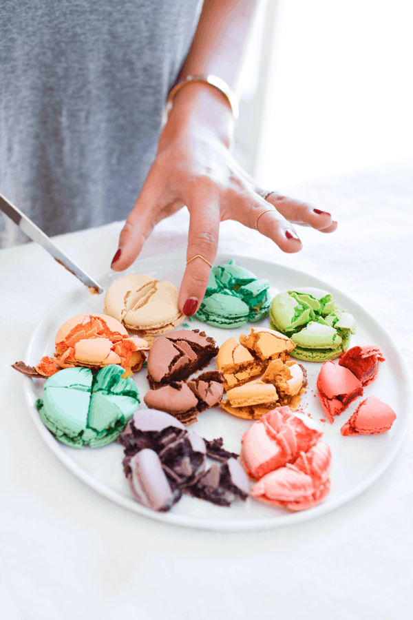 Woman cutting a variety of macarons to do a taste test.