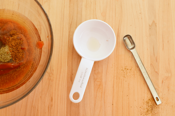 Overhead view of a measuring cup and spoon on a cutting board.