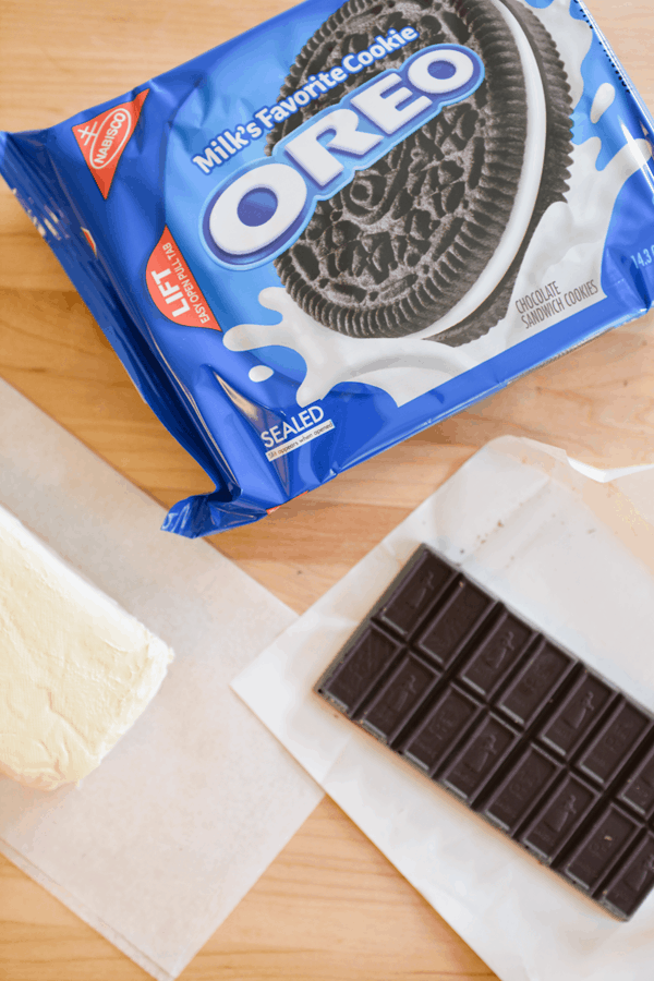 Overhead shot of a package of Oreos on a cutting next to a chocolate bar and cream cheese.